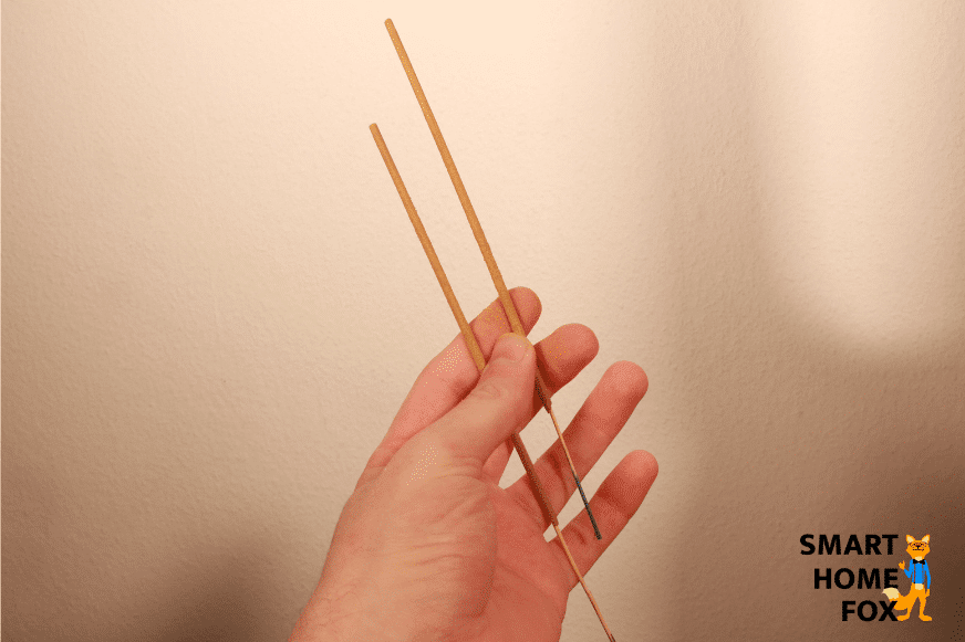 Zwei Räucherstäbchen werden in der Hand gehalten